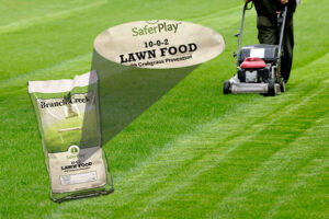 Branch Creek 10-0-2 Lawn Food product image with a magnified section showing SaferPlay 10-0-2 Lawn Food with Crabgrass Preventtion on ain image of green grass being mowed